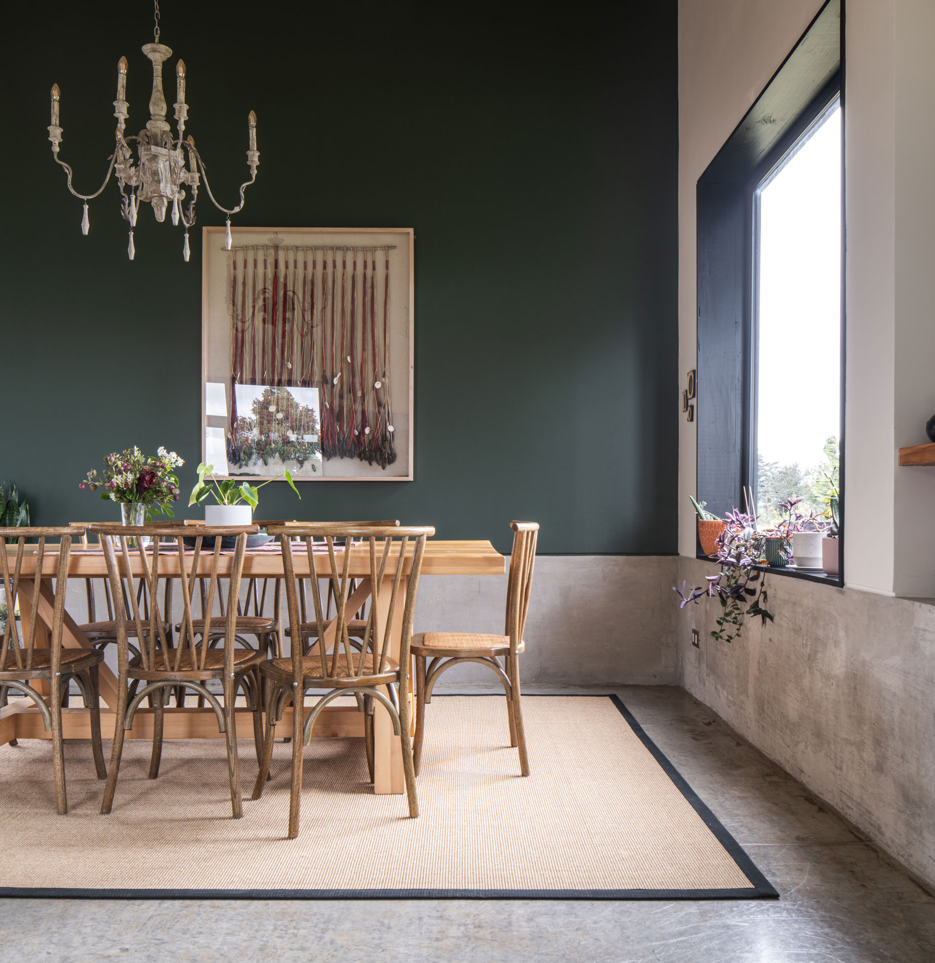 Comedor íntimo de madera con muro verde y ventana al paisaje. Casa Carpintero. LAGAR arqtos.